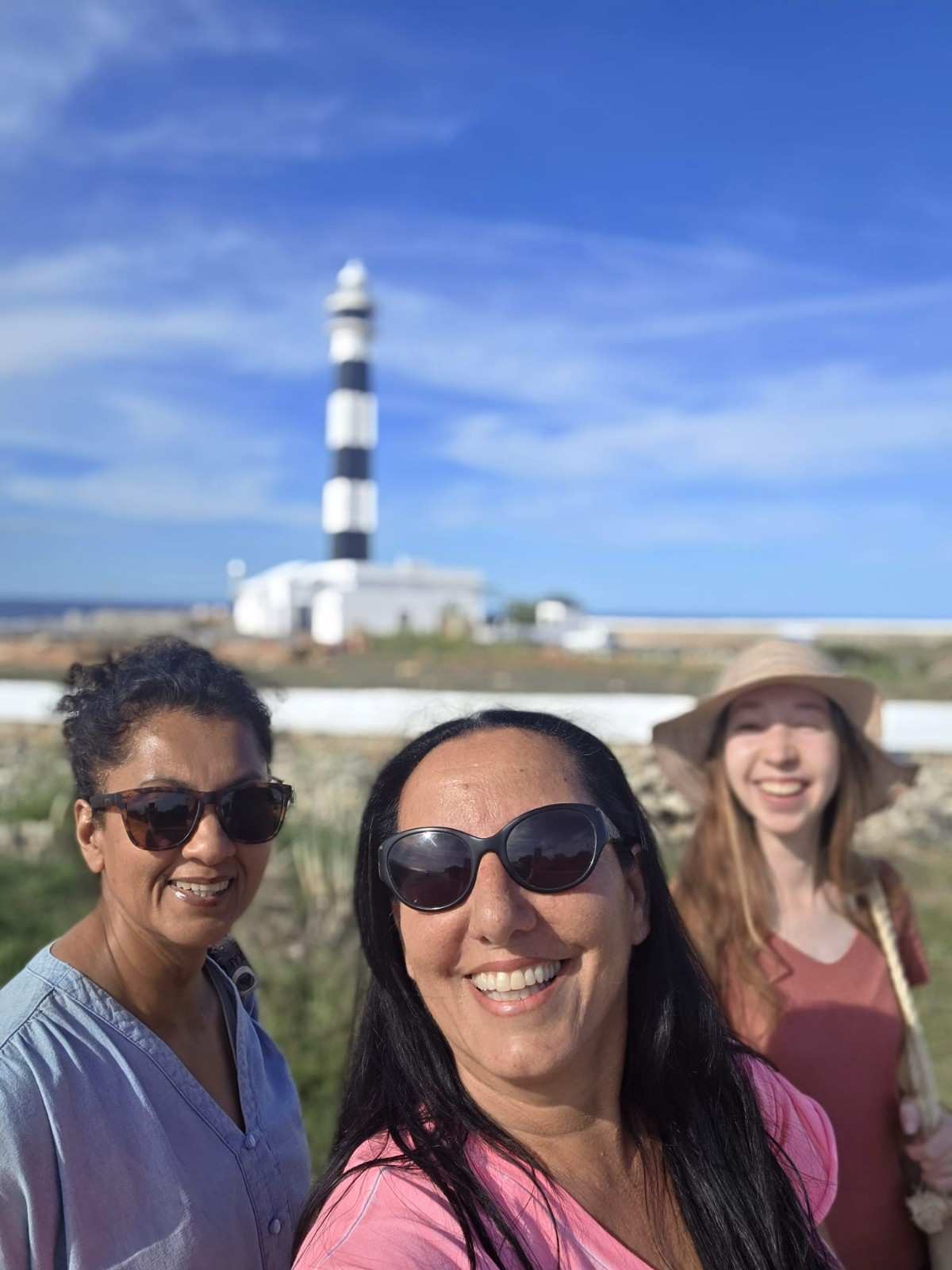 Students smiling beneath the Cap d'Artrutx lighthouse in Ciutadella, Menorca